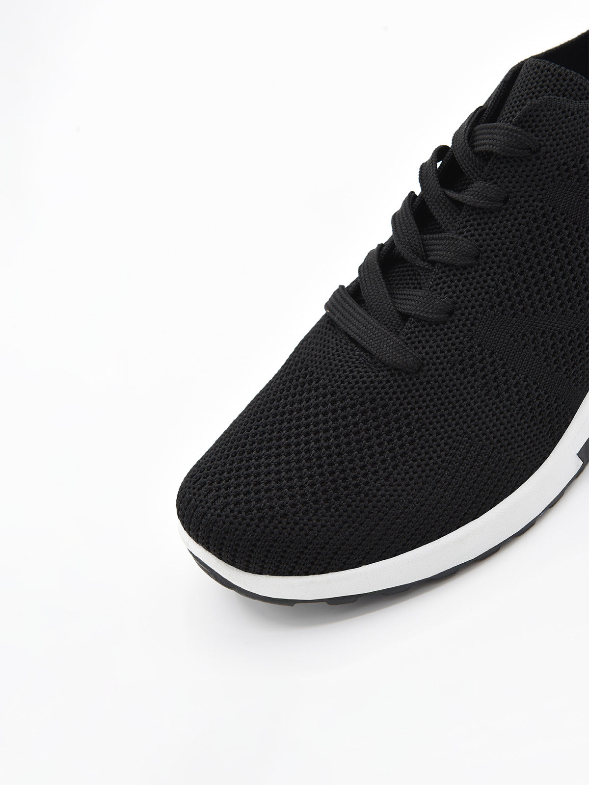 Zapatilla negra de tejido transpirable, con agujetas, plataforma bicolor blanca y negra, y detalle metálico en el talón.