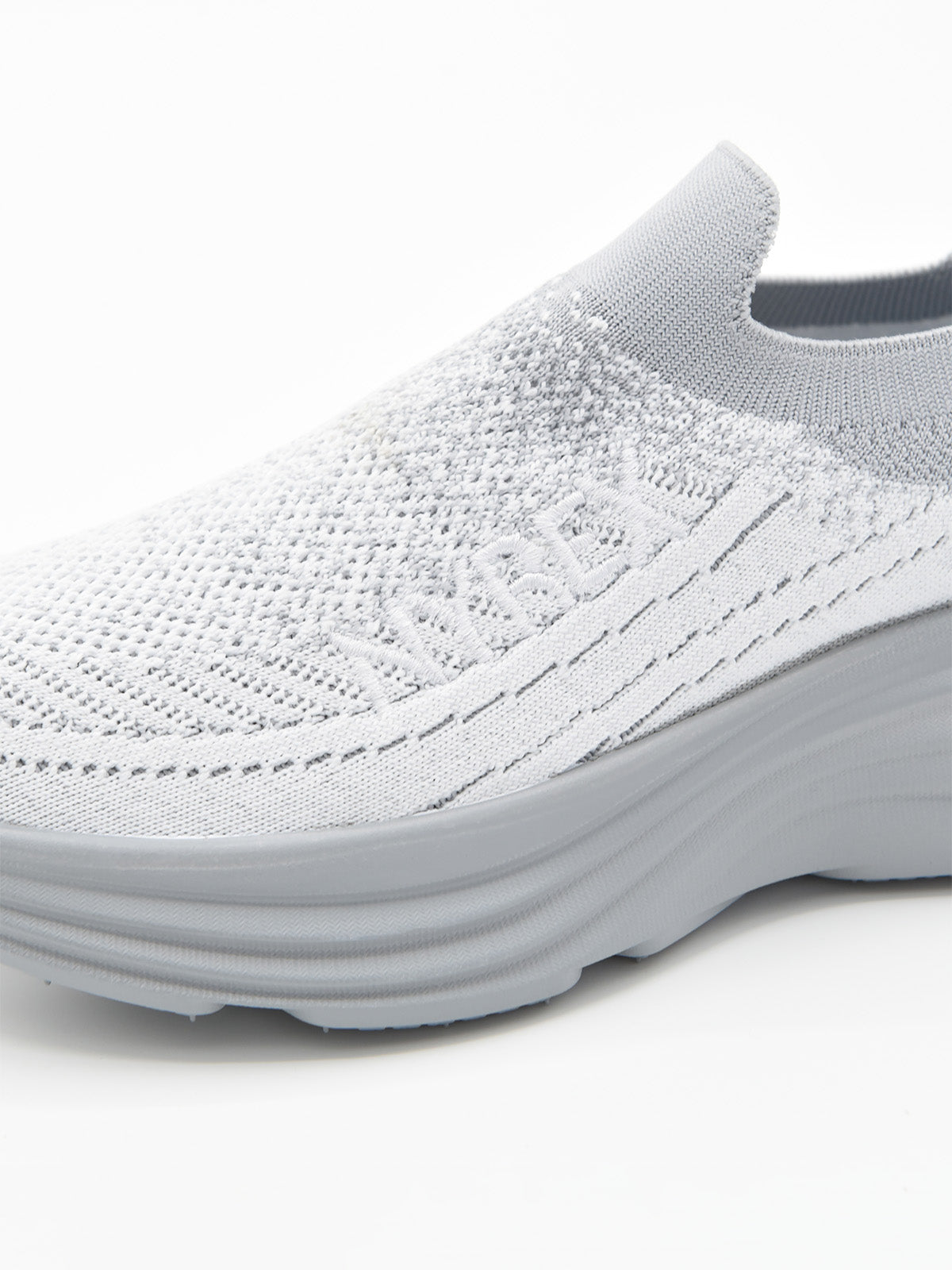 Zapatilla slip-on de punto knit en degradado gris con suela chunky ondulada gris y logo Nyrex en relieve.