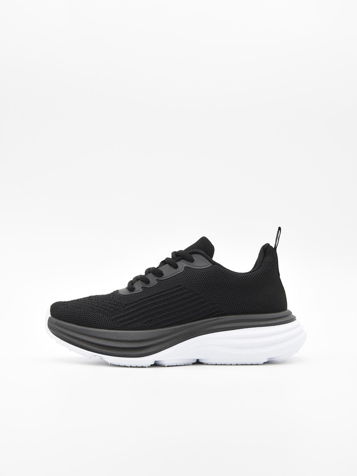 Zapatilla deportiva de tejido negro con cordones, suela gruesa blanca y detalles en negro en la base.