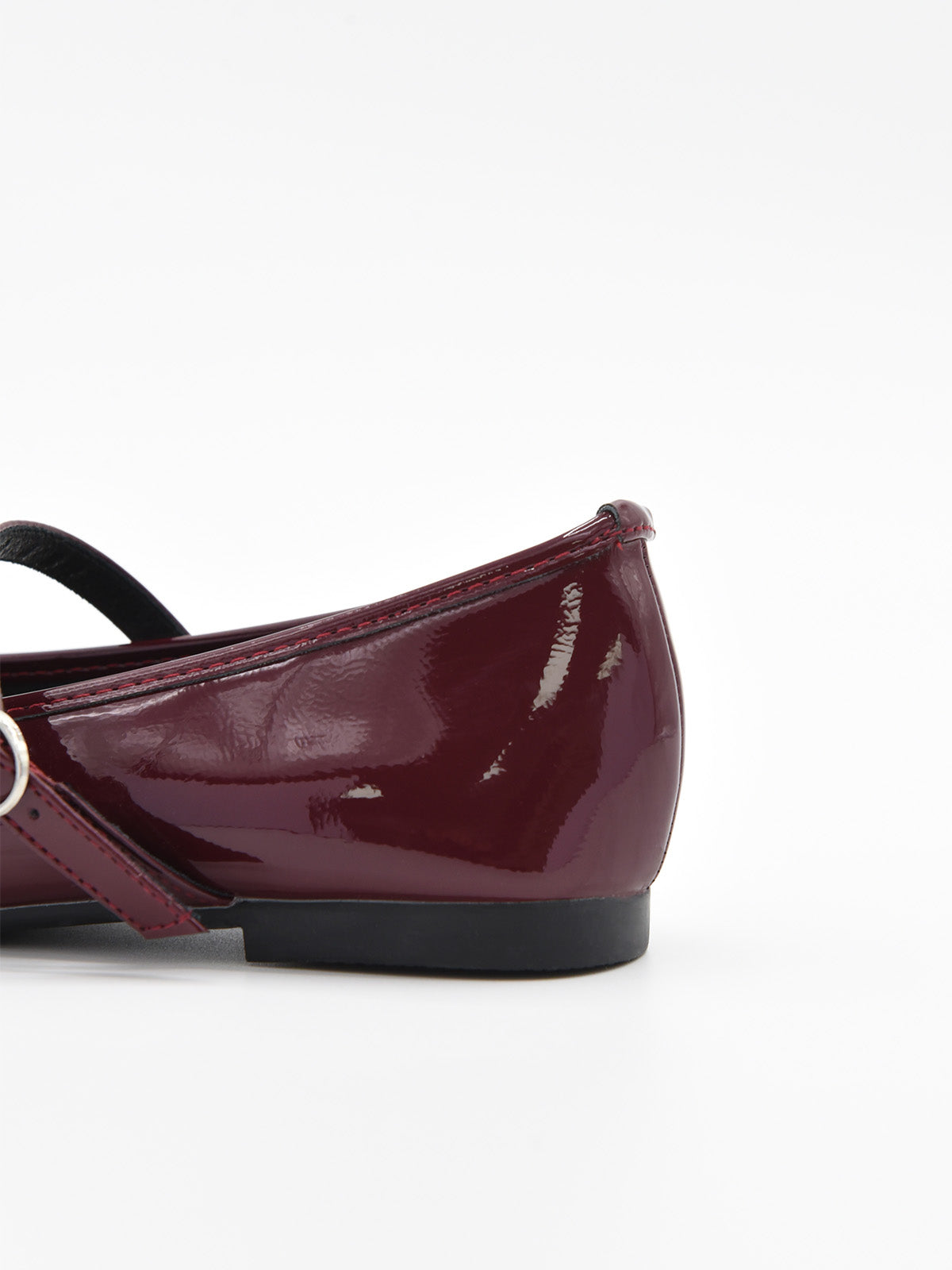 Zapato plano tipo bailarina en charol burdeos con pulsera y hebilla lateral.