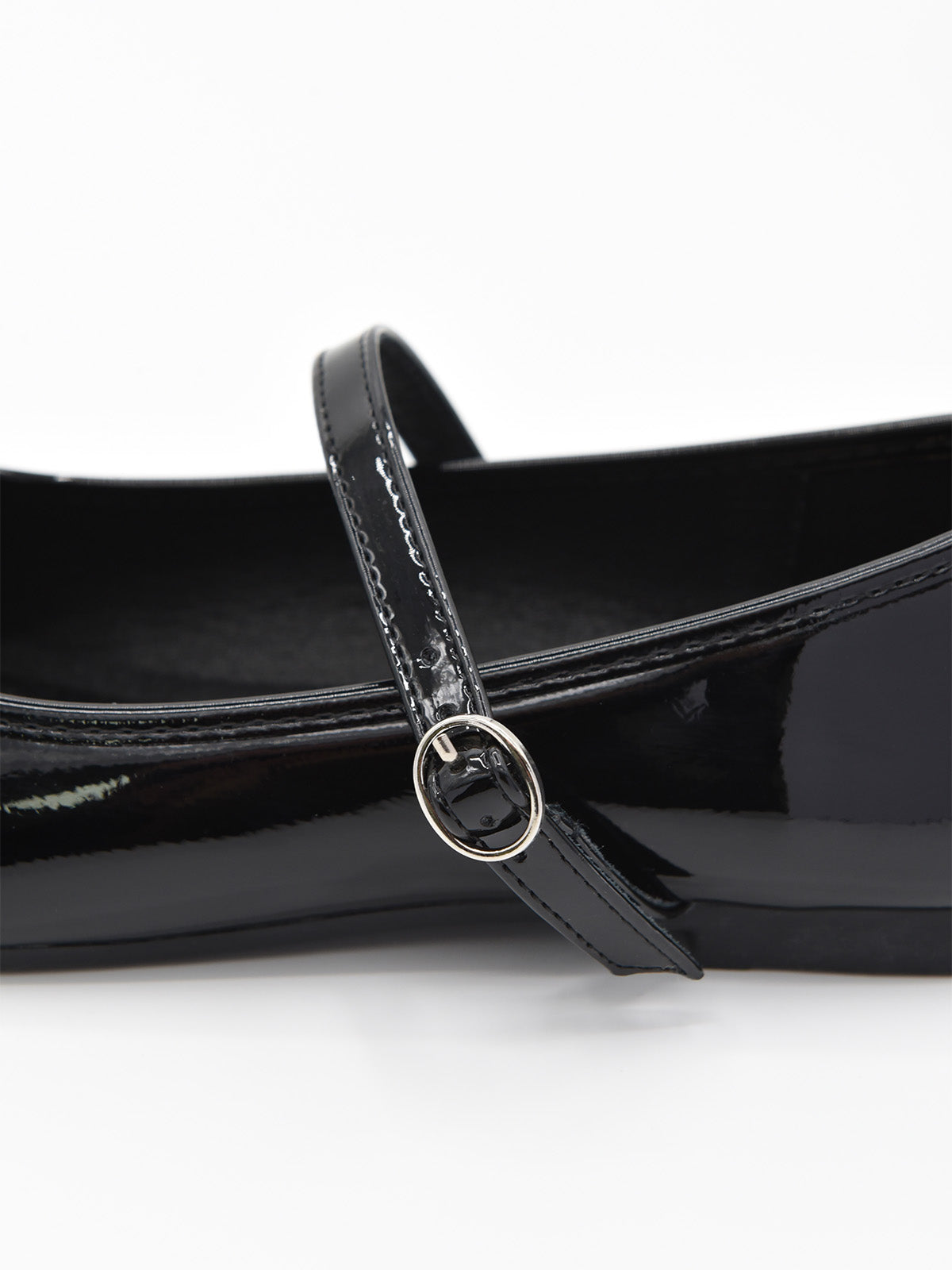 Bailarina negra de charol con pulsera fina y hebilla metálica en el lateral.
