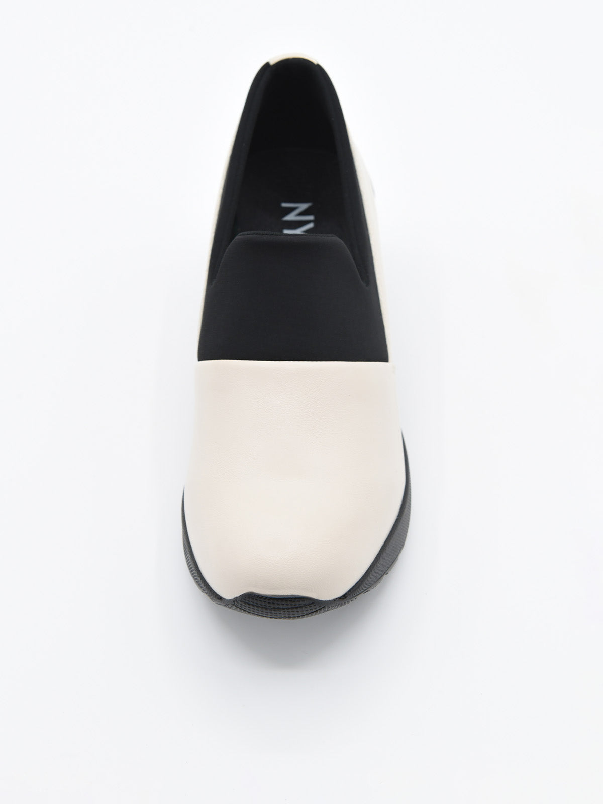 Zapato casual bicolor para mujer, en tonos crema y negro, estilo slip-on con elástico superior y plataforma ergonómica continua.