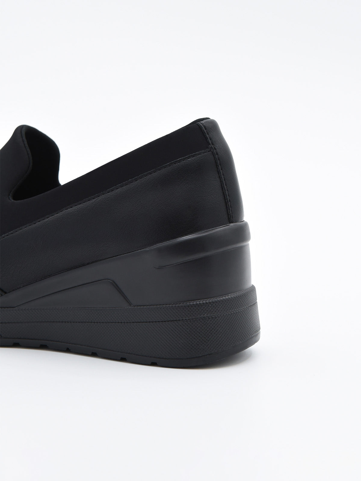 Zapato casual negro para mujer, estilo slip-on con elástico superior y plataforma ergonómica continua.