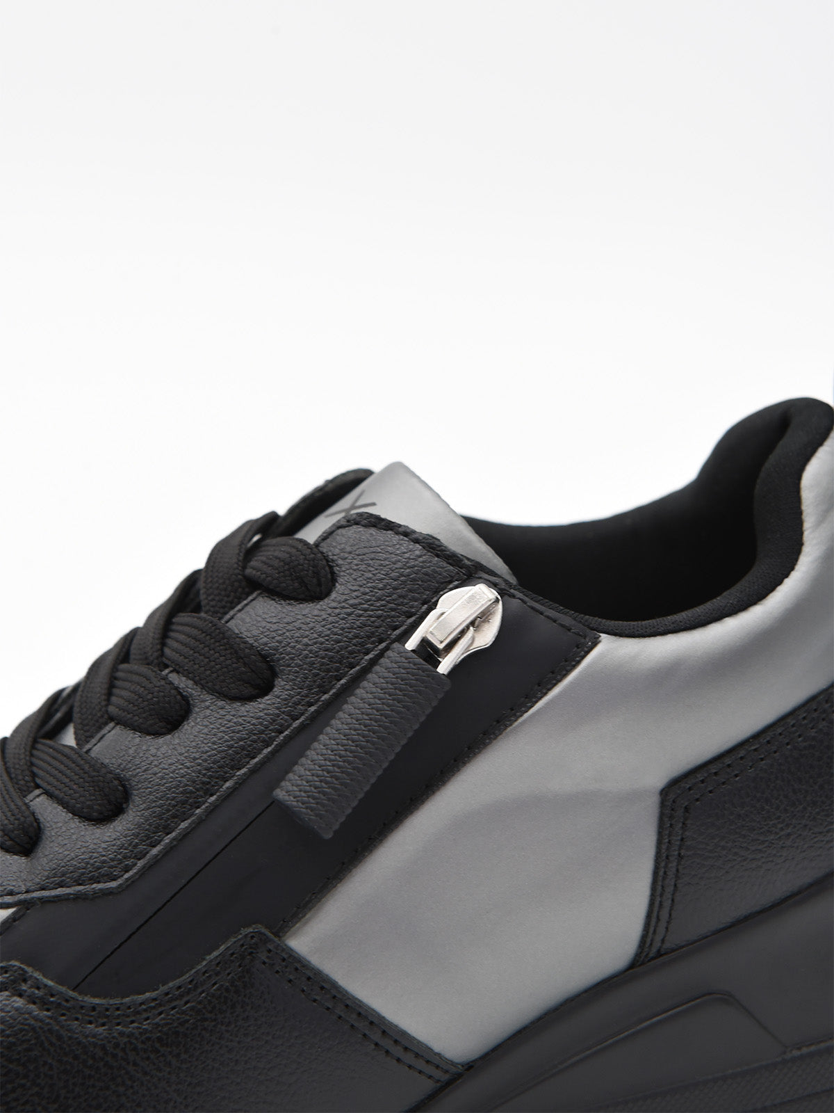 Zapatillas casual negras para mujer con plataforma ergonómica, agujetas y detalles metálicos decorativos en el lateral.