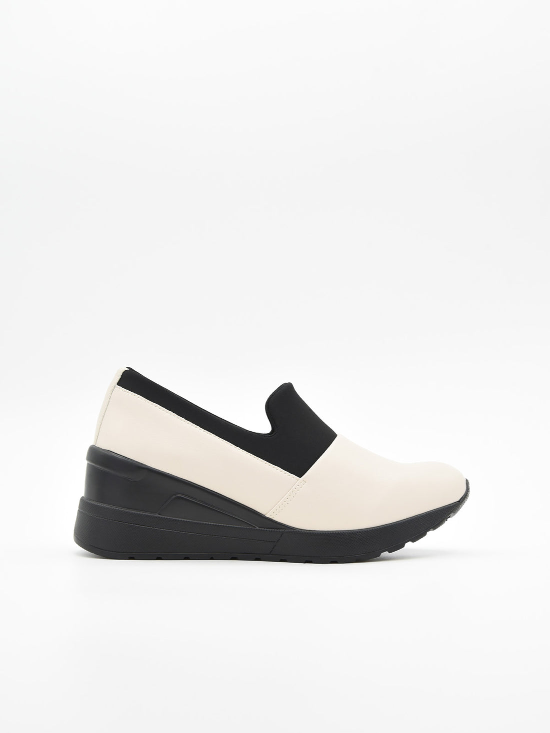 Zapato casual bicolor para mujer, en tonos crema y negro, estilo slip-on con elástico superior y plataforma ergonómica continua.
